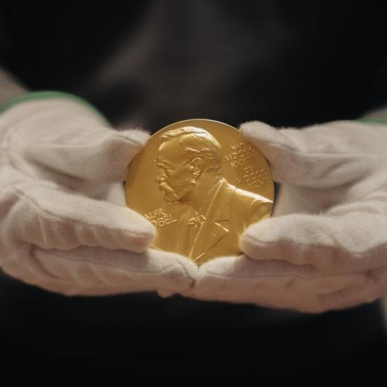 Nobelmedaljen holdes med handsker.