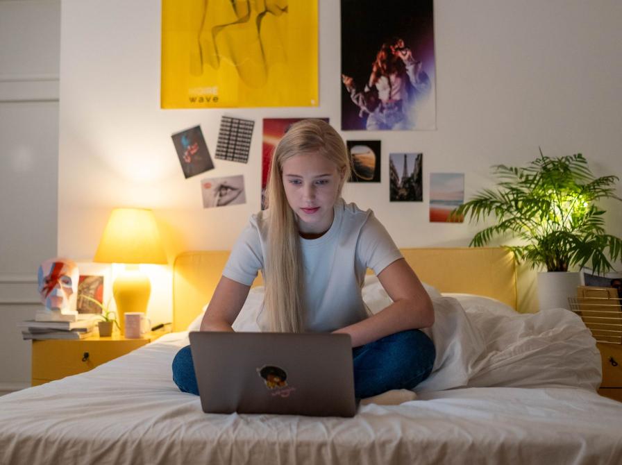 Teenagepige i seng med computer